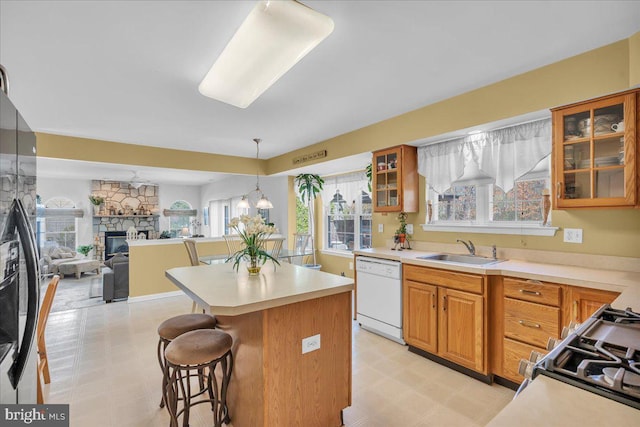 kitchen with dishwasher, a sink, light countertops, a kitchen breakfast bar, and light floors
