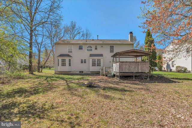 back of house with a chimney, a fire pit, and a lawn