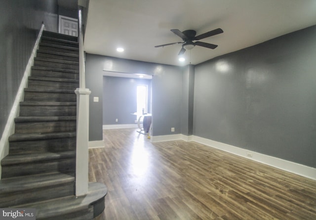 interior space with ceiling fan, baseboards, wood finished floors, and stairs