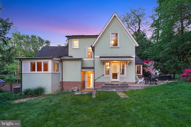 7812 Takoma Ave, Takoma Park, MD 20912 - back of house at dusk featuring stucco siding, brick siding, a lawn, and a shingled roof