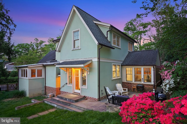 7812 Takoma Ave, Takoma Park, MD 20912 - back of property at dusk featuring roof with shingles, stucco siding, and a patio area