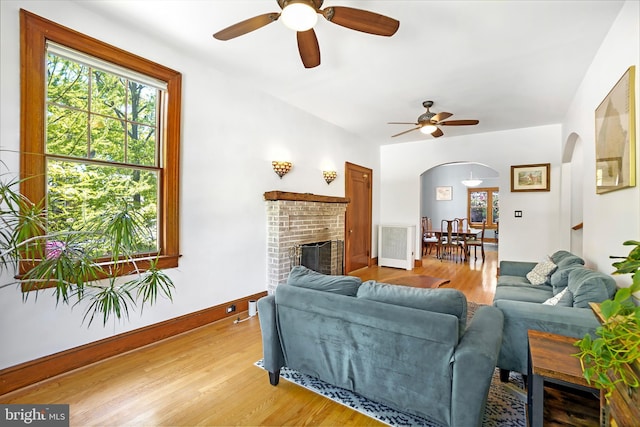 7812 Takoma Ave, Takoma Park, MD 20912 - living room with arched walkways, ceiling fan, light wood-type flooring, and a brick fireplace