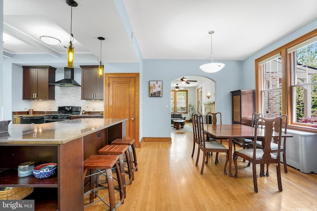 7812 Takoma Ave, Takoma Park, MD 20912 - kitchen with black gas range, wall chimney range hood, arched walkways, light wood-style flooring, and backsplash