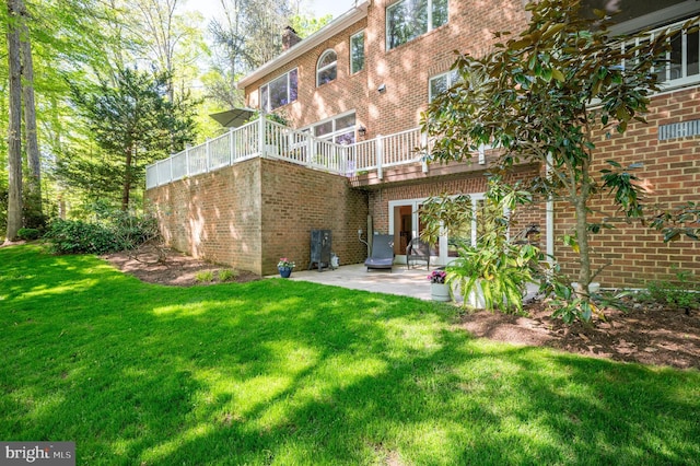 rear view of house with a lawn, a patio, and brick siding