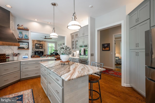 kitchen featuring wall chimney range hood, a breakfast bar area, and gray cabinetry