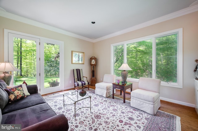 living room with crown molding, baseboards, wood finished floors, and a healthy amount of sunlight