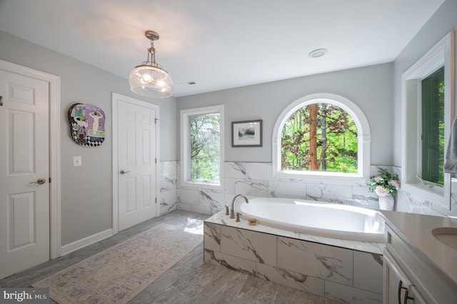 bathroom with a bath, visible vents, wainscoting, vanity, and marble finish floor