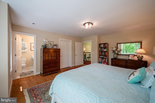 bedroom featuring connected bathroom, baseboards, and wood finished floors