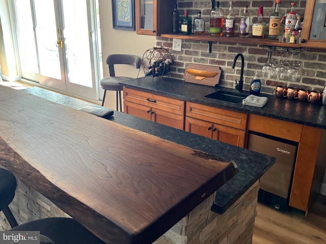 interior space with open shelves, brown cabinetry, a sink, and wood finished floors