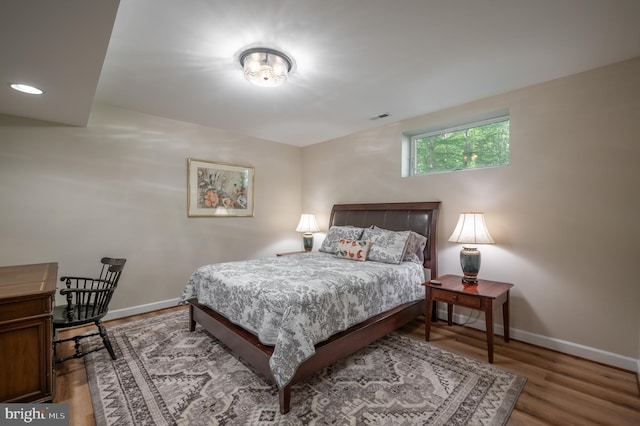 bedroom with visible vents, baseboards, and wood finished floors