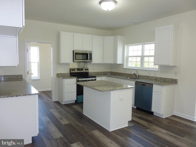 kitchen with appliances with stainless steel finishes, a sink, white cabinetry, and light stone countertops