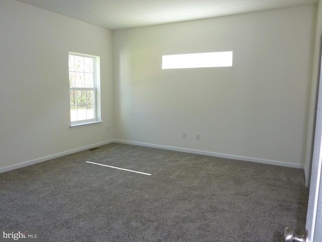 empty room with carpet floors, baseboards, and visible vents