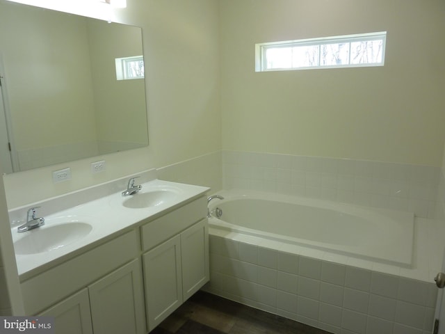 full bath featuring double vanity, a garden tub, and a sink