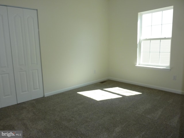 carpeted empty room featuring baseboards