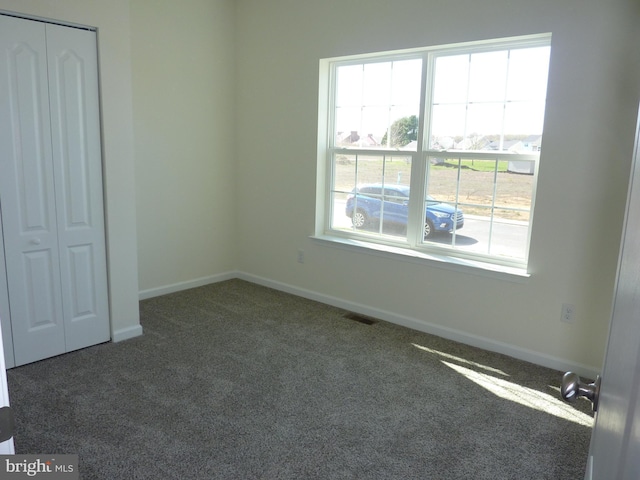 unfurnished bedroom with carpet flooring, visible vents, a closet, and baseboards