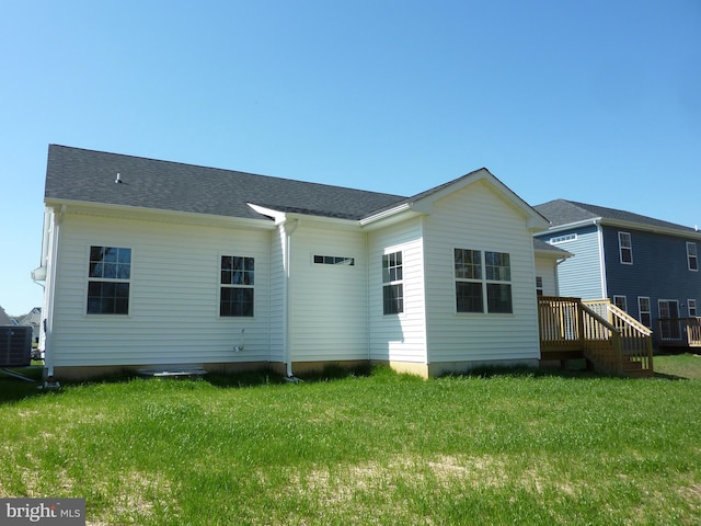 rear view of property featuring central AC, a shingled roof, and a lawn