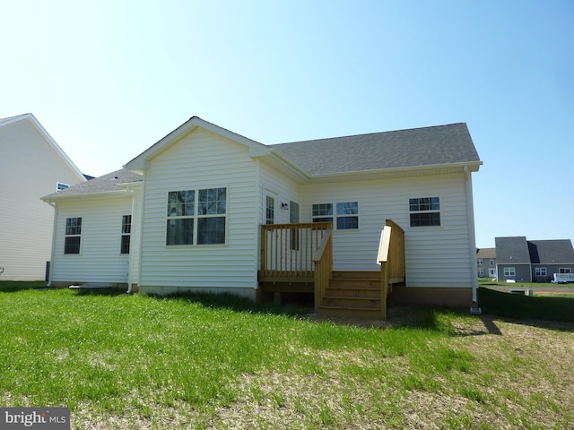back of house featuring a shingled roof, a wooden deck, and a yard