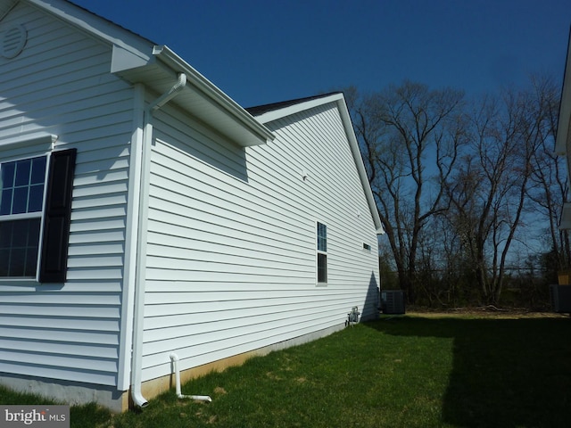 view of side of property featuring cooling unit and a yard