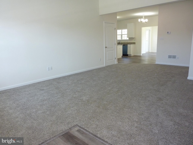 unfurnished living room featuring visible vents, baseboards, dark colored carpet, and an inviting chandelier