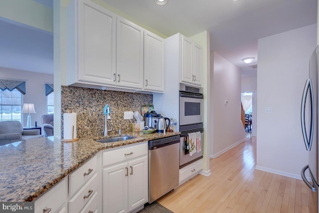 10 Cavendish Ct, Rehoboth Beach, DE 19971 - kitchen with stainless steel appliances, a sink, decorative backsplash, light stone counters, and white cabinets