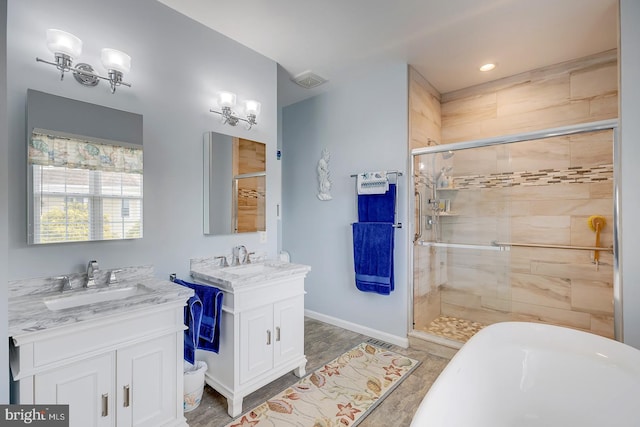 10 Cavendish Ct, Rehoboth Beach, DE 19971 - bathroom with two vanities, a shower stall, a soaking tub, baseboards, and recessed lighting