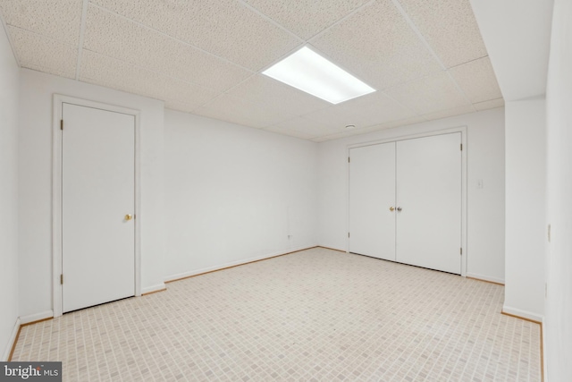unfurnished room featuring baseboards and a drop ceiling