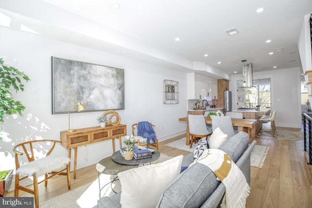 living room featuring baseboards, light wood-style floors, and recessed lighting