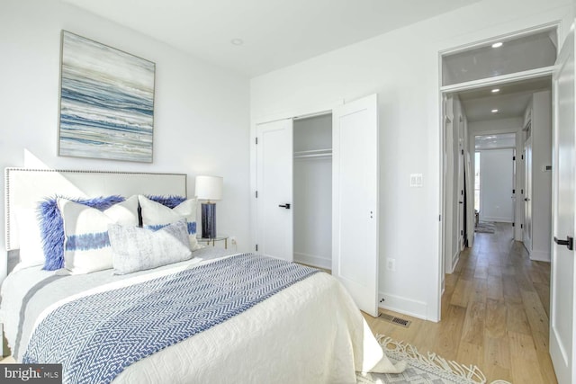bedroom with a closet, baseboards, and light wood-style floors