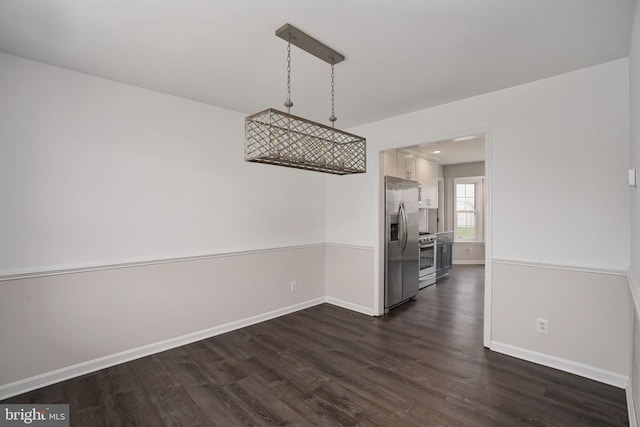 unfurnished dining area featuring baseboards and dark wood finished floors