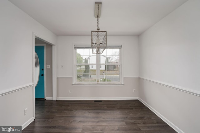 unfurnished dining area featuring baseboards, dark wood-style flooring, visible vents, and a chandelier