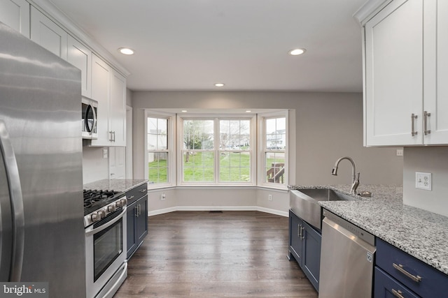 kitchen with white cabinetry, blue cabinets, light stone counters, and appliances with stainless steel finishes