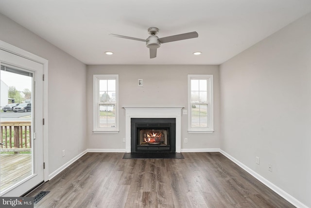 unfurnished living room with plenty of natural light, a fireplace with flush hearth, baseboards, and dark wood finished floors