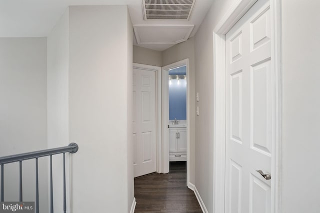 hall featuring dark wood finished floors, baseboards, and visible vents