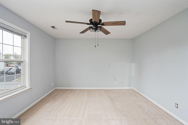 carpeted empty room with baseboards, visible vents, and ceiling fan