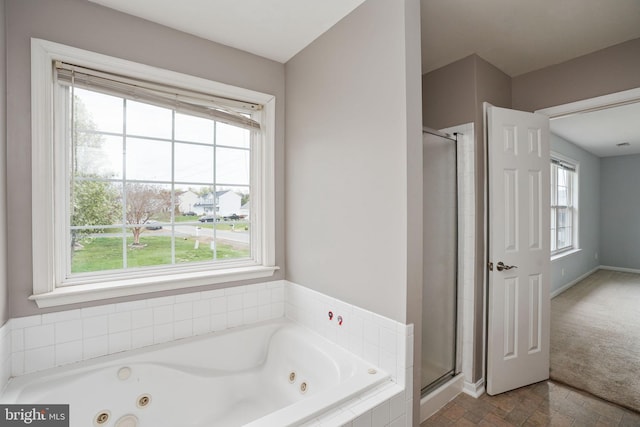 bathroom featuring a shower stall, a tub with jets, and baseboards