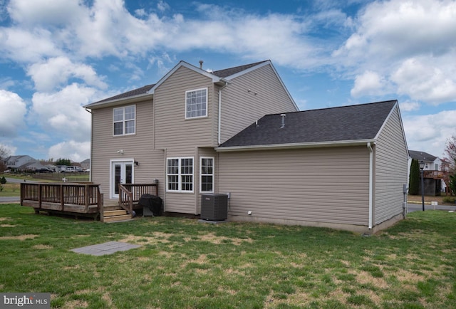 rear view of property with roof with shingles, cooling unit, a deck, and a yard
