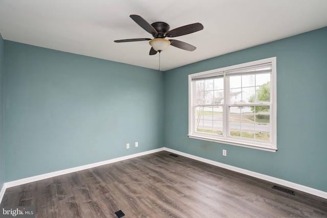 spare room with baseboards, dark wood-style floors, visible vents, and ceiling fan