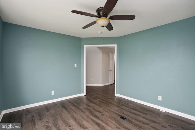 spare room featuring a ceiling fan, baseboards, and dark wood finished floors