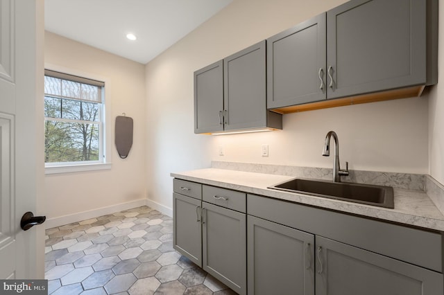 kitchen featuring a sink, light countertops, baseboards, gray cabinetry, and recessed lighting