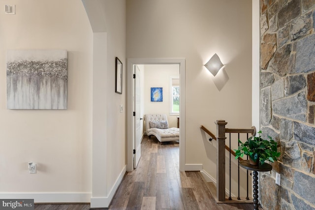 hall with baseboards, wood finished floors, and an upstairs landing