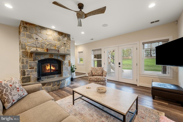 living room featuring wood finished floors, visible vents, a ceiling fan, and a healthy amount of sunlight