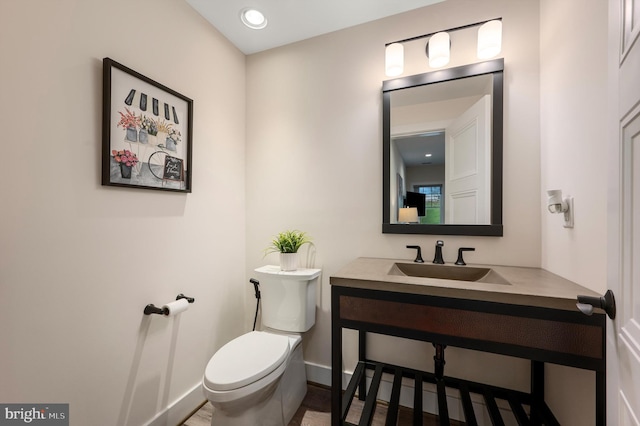 half bathroom featuring toilet, a sink, and baseboards