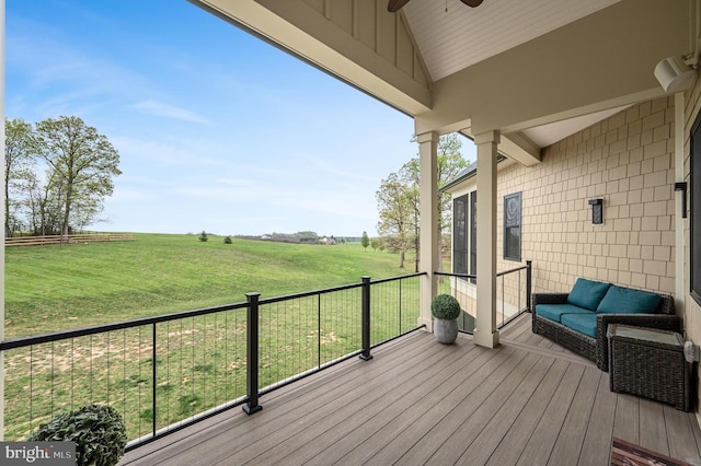 wooden deck featuring a rural view, a lawn, and ceiling fan