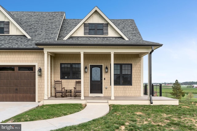 view of front of home featuring a front lawn, covered porch, roof with shingles, and concrete driveway