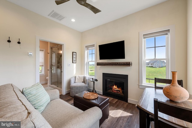 living room featuring plenty of natural light, visible vents, a glass covered fireplace, and ceiling fan