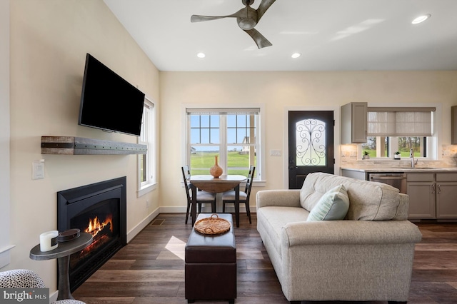 living area featuring dark wood-style floors, baseboards, recessed lighting, a ceiling fan, and a lit fireplace