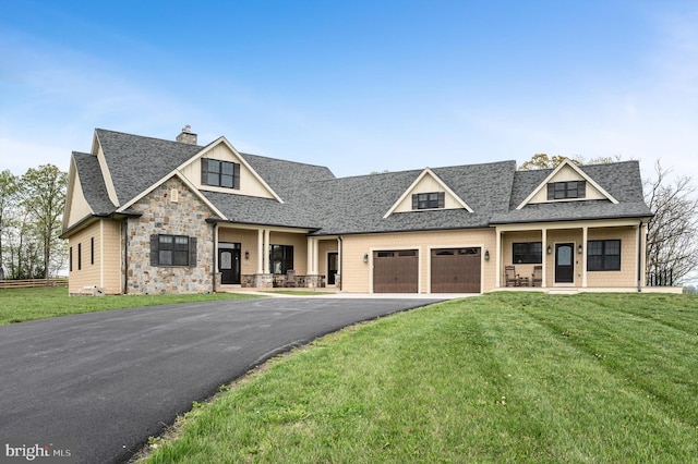 craftsman-style house featuring a garage, driveway, a porch, and a front yard