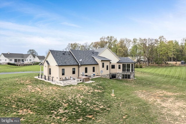 rear view of property with board and batten siding, a lawn, and a shingled roof