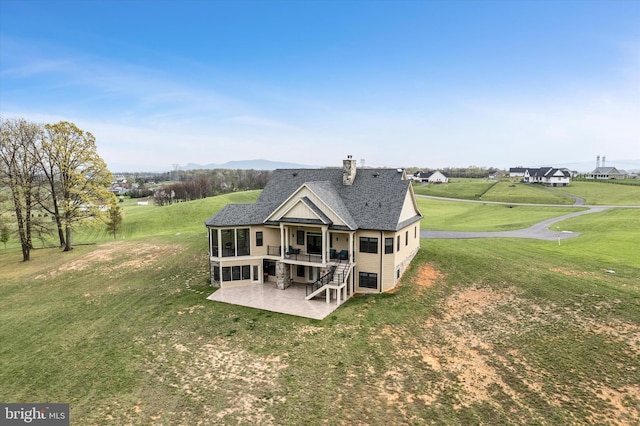 back of property with stairway, a chimney, a lawn, a shingled roof, and a patio