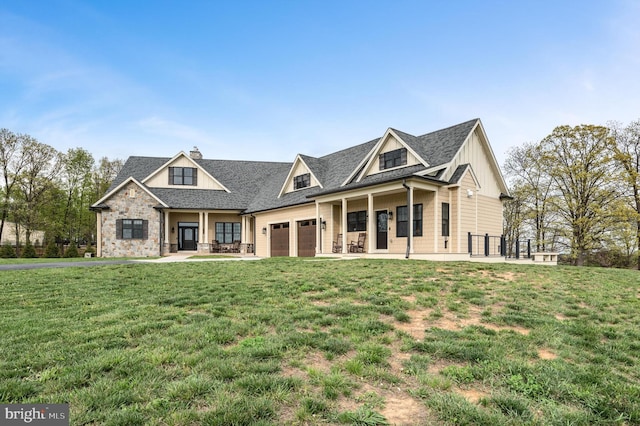 view of front of home featuring an attached garage, covered porch, a front yard, and board and batten siding